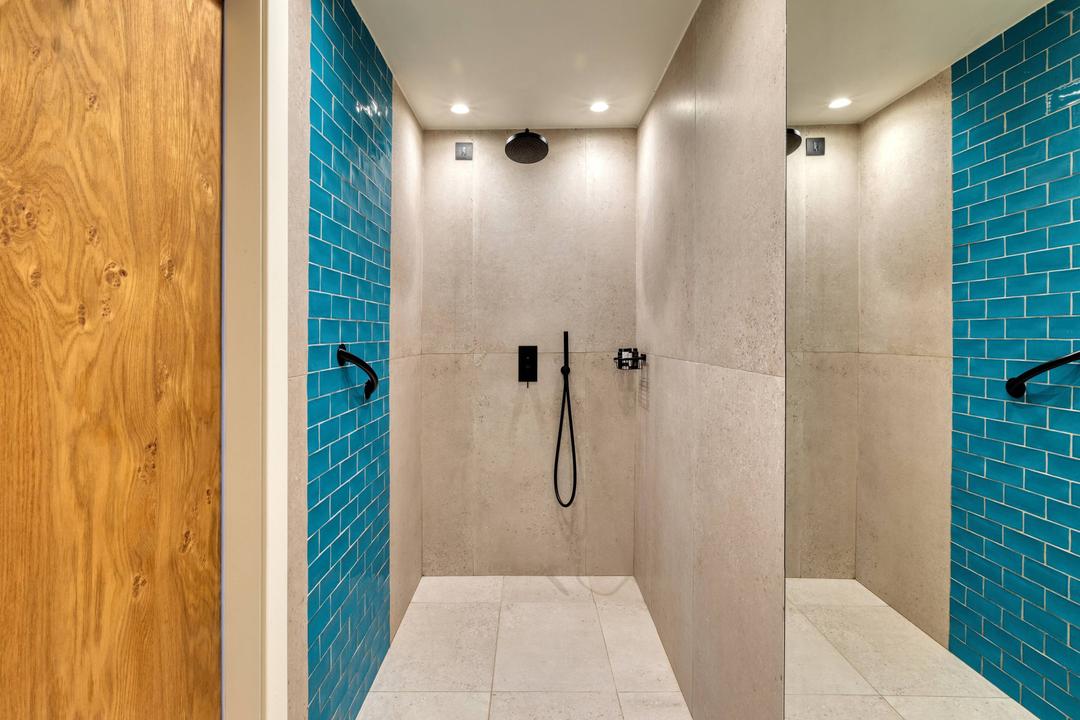 A spacious bathroom with a walking shower with a unique design.