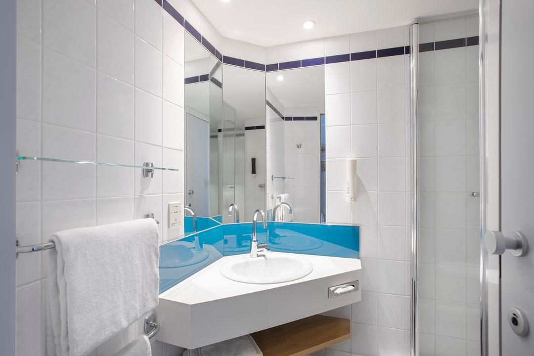 A sparkling white-tiled bathroom in a standard room.